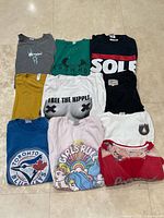 Group shot of all ten graphic T-shirts laid flat