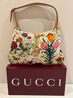 Front view of Gucci floral canvas shoulder bag on branded box