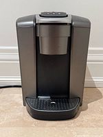 Front view of Keurig K-Elite coffee maker showing housing, brew head and drip tray