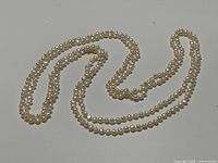 Two matching freshwater pearl necklaces coiled on a flat surface