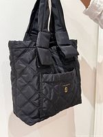Front and side profile of black quilted tote showing shape and handles