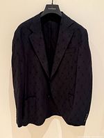 Full front view of black embroidered blazer on hanger