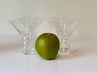 All four Riedel stemless martini glasses with apple for scale