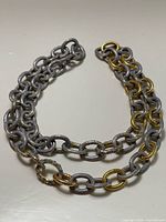 Full view of grey and gold tone chain link necklace laid flat