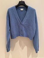 Front view of blue cropped cardigan on hanger
