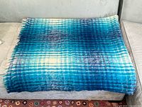 Full view of folded turquoise and blue mohair plaid throw on sofa