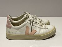 Lateral view of both sneakers showing white leather, pink logos, outsole wear