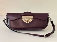 Front view of plum Epi leather Montaigne clutch with strap attached