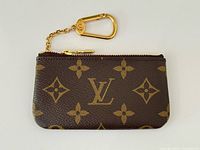 Front view of Louis Vuitton monogram key pouch showing LV logo pattern and zipper