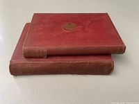 Two red cloth miniature books stacked