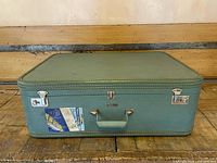 Closed suitcase front showing handle, latches, sticker