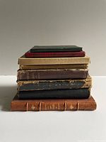 Stack of eight antique books showing varied bindings and spine wear
