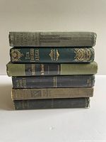 Stack of six antique hardcover books showing spines