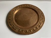 Front view of hammered copper charger showing geometric border