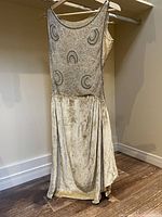 Full view of sleeveless ivory velvet flapper dress on hanger