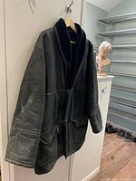 Full view of sheepskin coat on hanger showing overall design and length