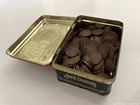 Open Jack Daniel's tin showing quantity of Canadian pennies