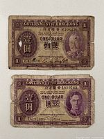 Fronts of both $1 Hong Kong notes showing portraits and serial numbers