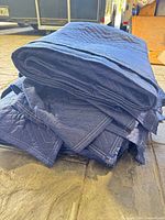 Stack of folded blue quilted moving blankets