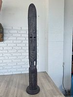 Full view of tall carved wooden fertility statue on base