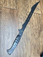 Full view of machete showing blade shape, taped handle and lanyard slot