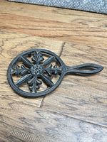 Front view of cast iron trivet showing full design and handle
