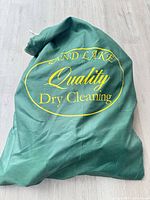 Full view of green nylon dry cleaning sack with printed logo
