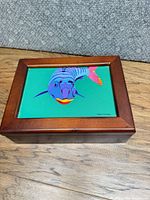 angled view of closed box showing wood frame and fish artwork under glass