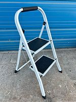 Full view of white 2-step folding stool outdoors