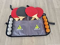Set opened showing four paddles, white balls, orange balls, case interior