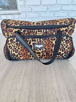 Full view of rolling duffel exterior showing leopard pattern and carry straps
