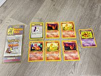 Overview of sealed sticker pack and seven loose cards laid out on floor