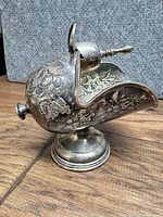Right side view of sugar scuttle showing floral engraving, scoop, pedestal base
