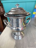 Front view of silver-plated ice bucket showing handles, pedestal, lid and finial