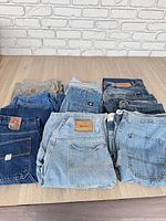 Group of folded jeans and pants showing quantity and brands