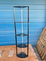 Full view of tall corner shelf showing four triangular shelves and white back post with cord
