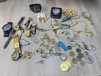Full layout of watches, jewelry, knives, barometer and coins on floor