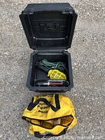Overall lot view: open plastic case with work light; yellow bag below