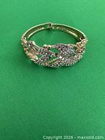 Top view of gold-tone hinged bangle showing rhinestone encrusted leafy design