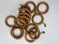 Pile of 14 wooden curtain rings with clips visible