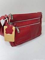 Front view showing red leather, dual front zip pockets, tag