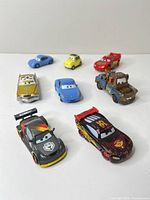 Group view of eight Disney Pixar Cars vehicles on white surface