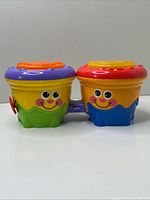 Front view of linked bongo drums showing smiling faces and connection piece