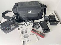 Group shot of camcorder, bag, chargers, battery, tape, manual and cords