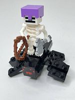 Front view of skeleton minifigure on spider with bow and sword