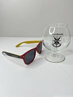 Brandy glass with crest beside sunglasses