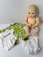 Front view of doll seated with clothing and diaper laid out