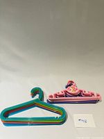 stack of multicolor plastic hangers and stack of pink Disney Tinker Bell hangers