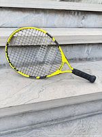 Full view of yellow/black Babolat junior racket on steps