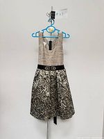 Front view of black and gold brocade girls dress on hanger